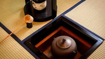 A traditional Japanese tea set on a tatami mat with a black tray and a teapot.
