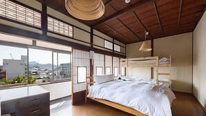 A modern bedroom with a bunk bed, wooden desk, and large windows offering a city view. - Yamamo Onomichi (Onomichi)