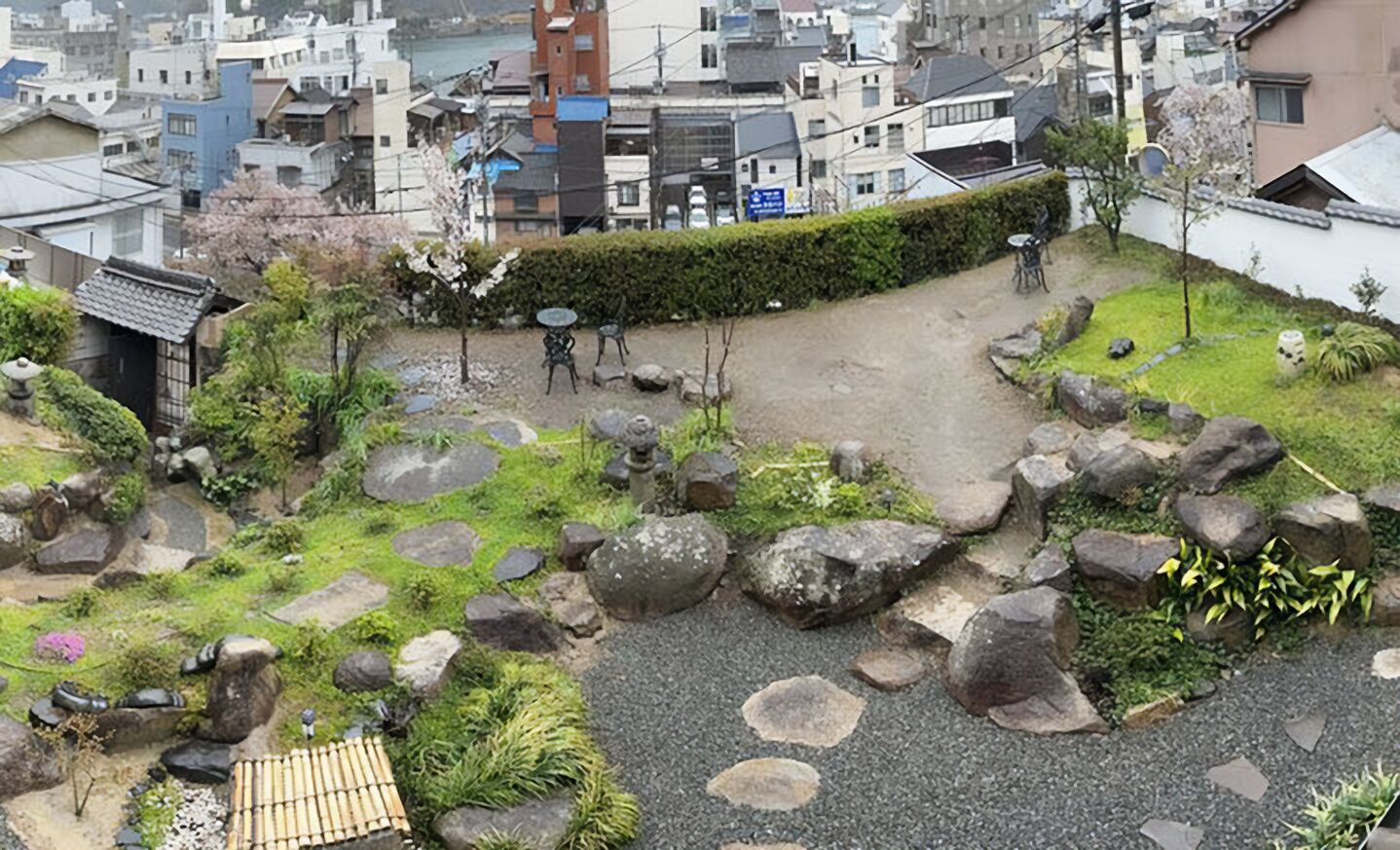 A courtyard with a traditional Japanese garden, including rocks, moss, and a small wooden structure.