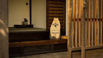 A wooden bench with a welcome sign in front of a traditional Japanese sliding door.