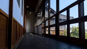 A corridor with wooden paneling and large windows. - Yamamo Onomichi (Onomichi)