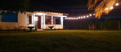 Una casa con fachada blanca, un porche cubierto y luces colgantes.