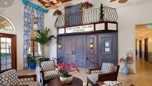 Un hall d'entrée avec un balcon, des meubles à motifs et une enseigne indiquant « Paradise Palms Cinema ».