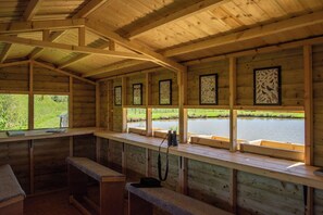 Una cabaña de madera con bancos y ventanas que dan a un cuerpo de agua.