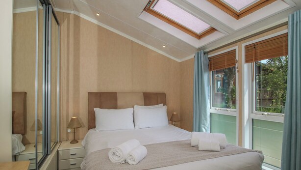 Une chambre d’hôtel avec un grand lit, une table de chevet, un miroir et une lucarne.