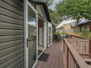 A deck with a table and chairs, a sliding glass door, and a wooden fence.