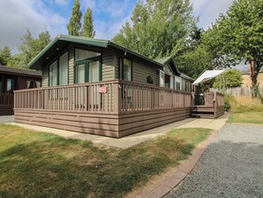 Une cabane dotée d’une terrasse, d’un porche couvert et d’un petit espace extérieur aménagé pour s’asseoir.