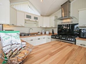 A modern kitchen with white cabinets, a wooden countertop, a stainless steel range hood, and a bag of instant hot chocolate.