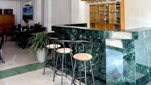 A bar area with a marble counter, three bar stools, and a wine glass display. - Hotel Prince Plaza - Laureles (Medellín)