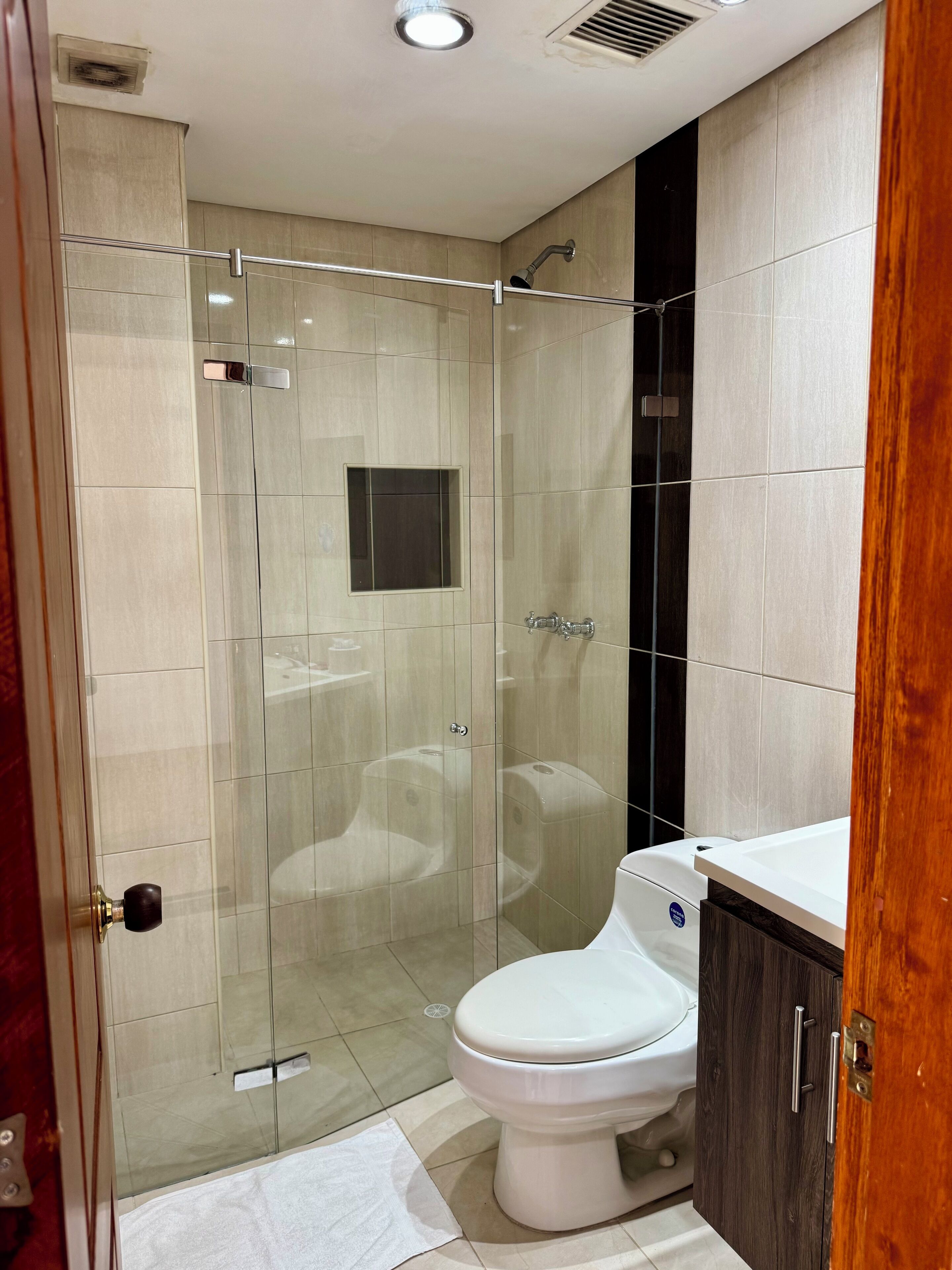 Une salle de bain moderne avec une douche à parois de verre, des toilettes blanches et un meuble en bois.