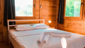 Une chambre dans une cabane en bois, avec un lit, une table de chevet et une fenêtre.