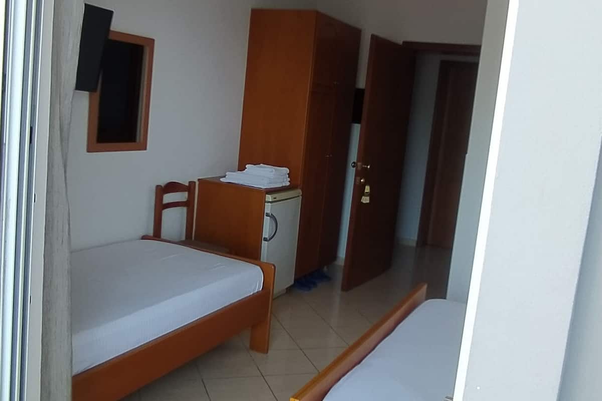 A room with two single beds, a small desk, a wardrobe, and a window with a curtain.