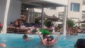 Una piscina amb paviment de rajola, gandules i ombrelles.
