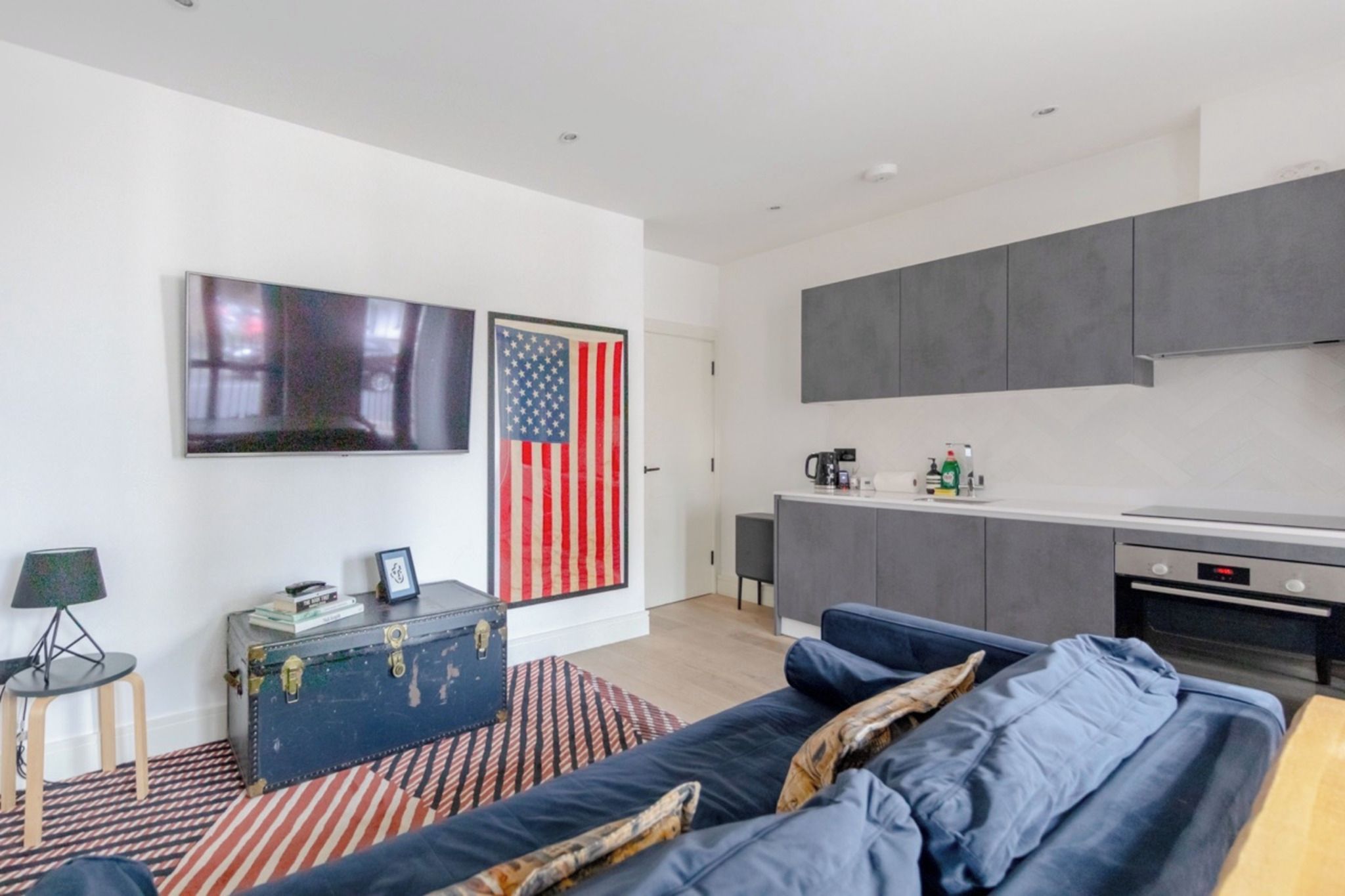 A modern living room with a sofa, a coffee table, a television, and a wall-mounted American flag.