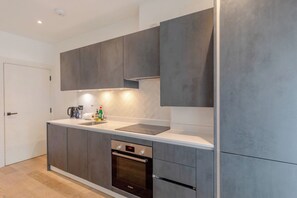 Een moderne keuken met grijze kastjes, een roestvrijstalen spoelbak en een inbouwoven.