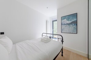 Een slaapkamer met een bed, een raam en een schilderij.
