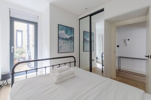 Ein modernes Schlafzimmer mit Bett, Balkon und Blick ins Freie.