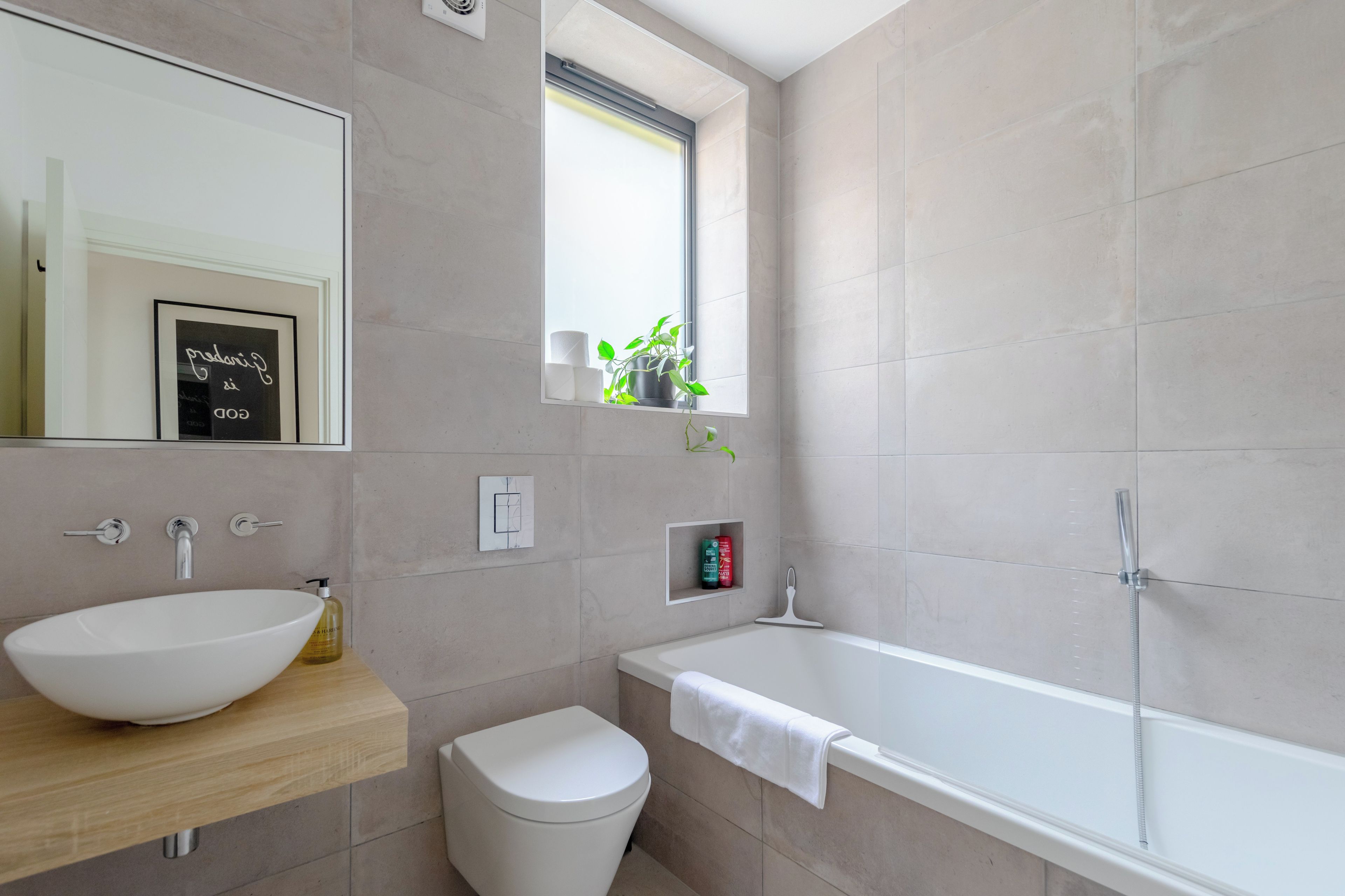 A modern bathroom with a large sink, toilet, and bathtub.