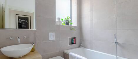 A modern bathroom with a large sink, toilet, and bathtub.