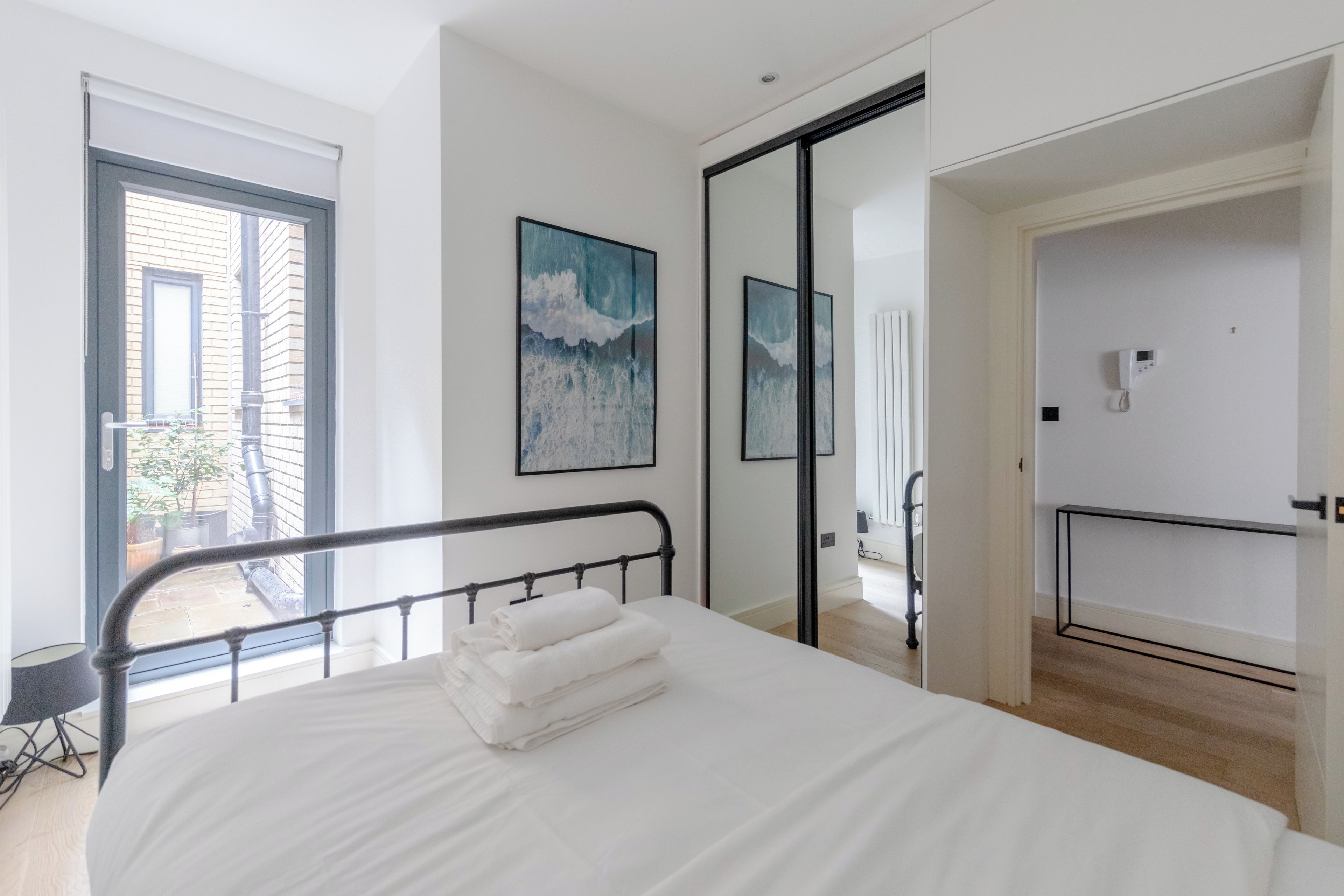 A modern bedroom with a bed, a balcony, and a view of the outside.