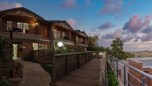A hotel with a wooden deck, brick exterior, and a view of the surrounding landscape. - Tembo Guest Lodge  (Mbombela)