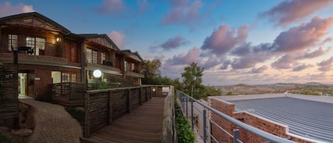 A hotel with a wooden deck, brick exterior, and a view of the surrounding landscape.
