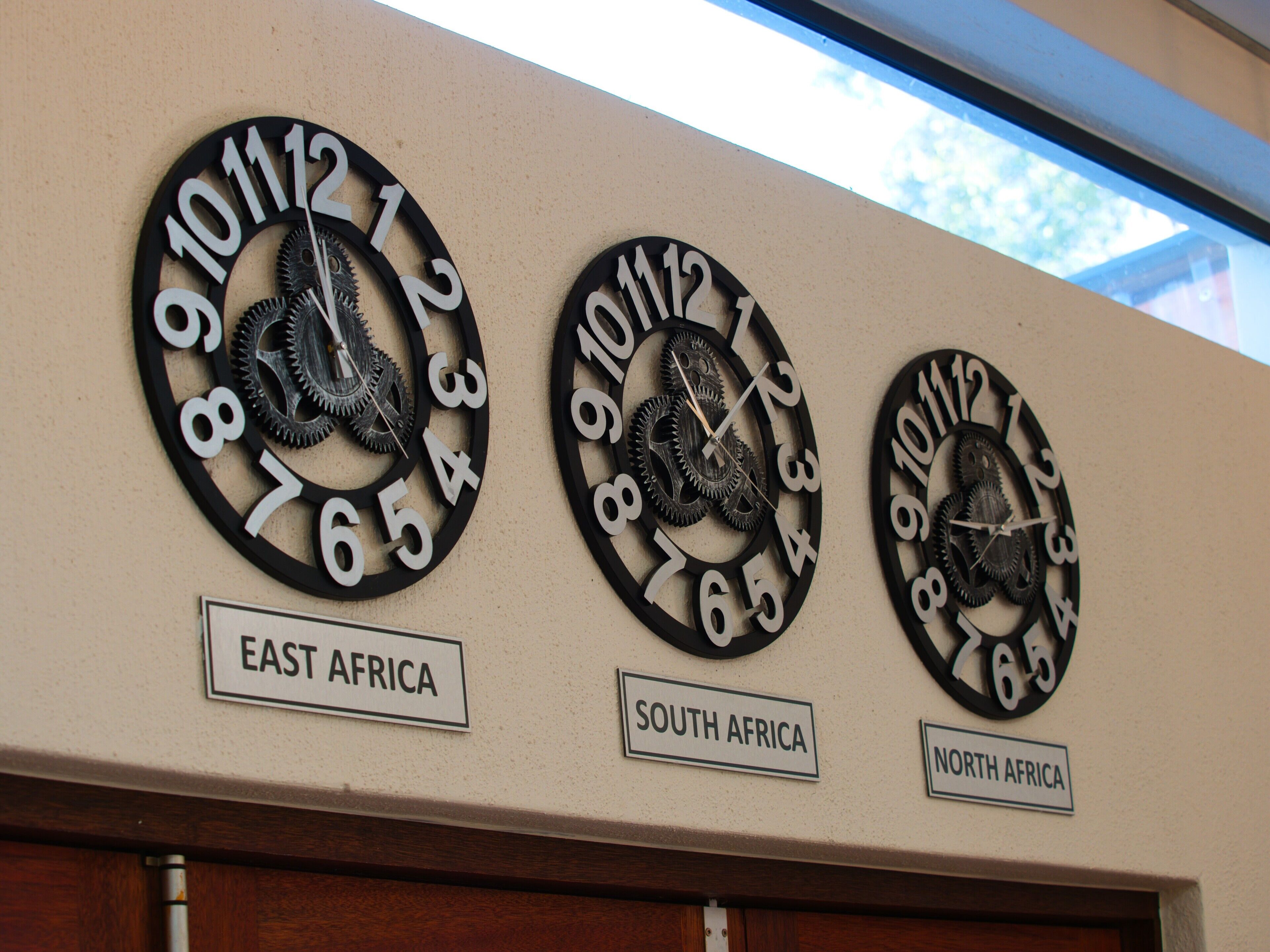 Three wall clocks with gears, each labeled with a different African region: East Africa, South Africa, and North Africa.