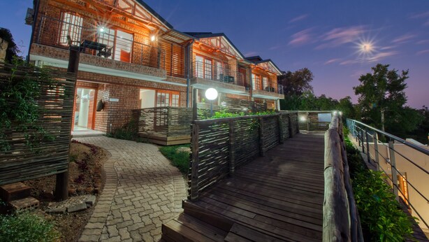 A two-story house with a wooden deck and a brick exterior. - Tembo Guest Lodge  (Mbombela)
