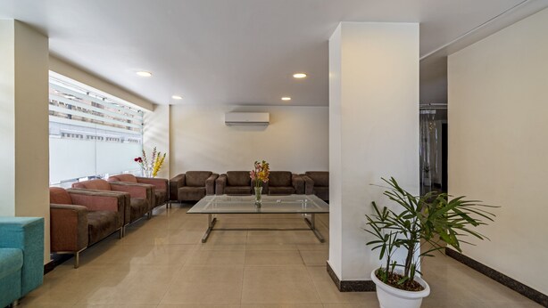 A modern waiting area with sofas, a coffee table, and a potted plant. - Treebo Premium Rose Mallow (New Delhi)