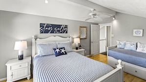 A bedroom with a bed, nightstands, a ceiling fan, and a door. - MultiDeck VIEWS *Sleeps 14* Pool & PingPong Table *Games Galore* *Fire-Pit* (Galveston)