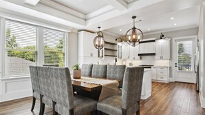 Una cocina moderna con armarios blancos, una isla de madera e iluminación colgante.