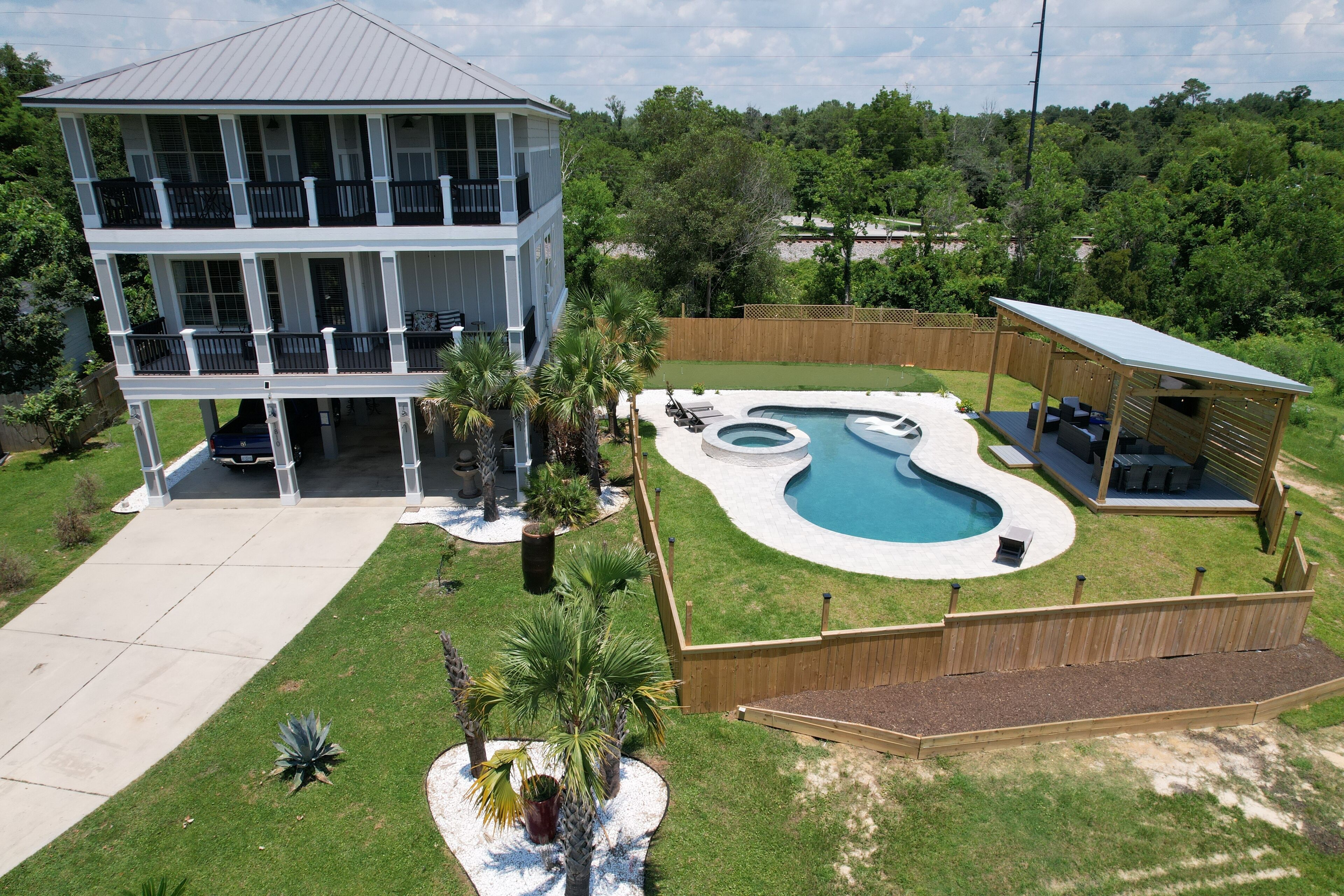 A two-story house with a swimming pool, a covered patio, and a fenced backyard.