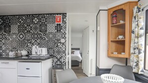 A modern kitchen with patterned backsplash tiles, a white refrigerator, and a coffee maker on the counter. - Rhiwlas Bach (Tyn-y-Gongl)