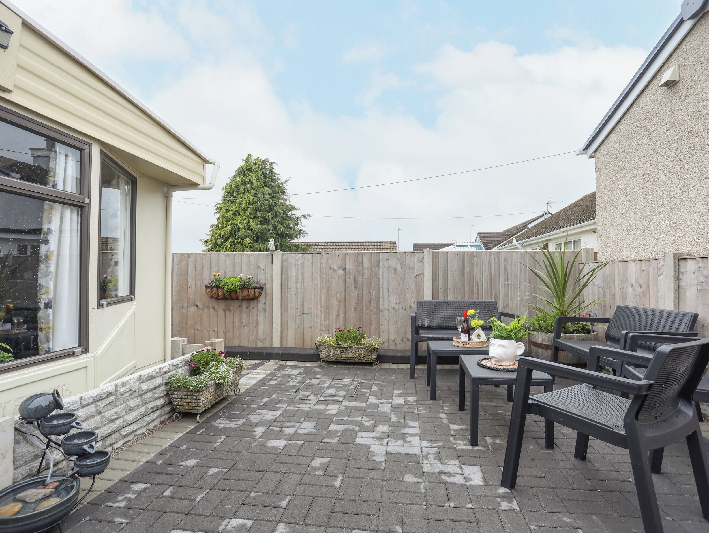 A patio area with a wooden fence, outdoor seating, and potted plants.