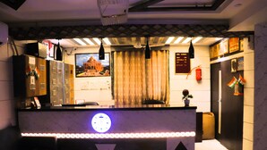 A hotel reception area with a marble counter, a clock, a framed picture of a building, and a curtain.