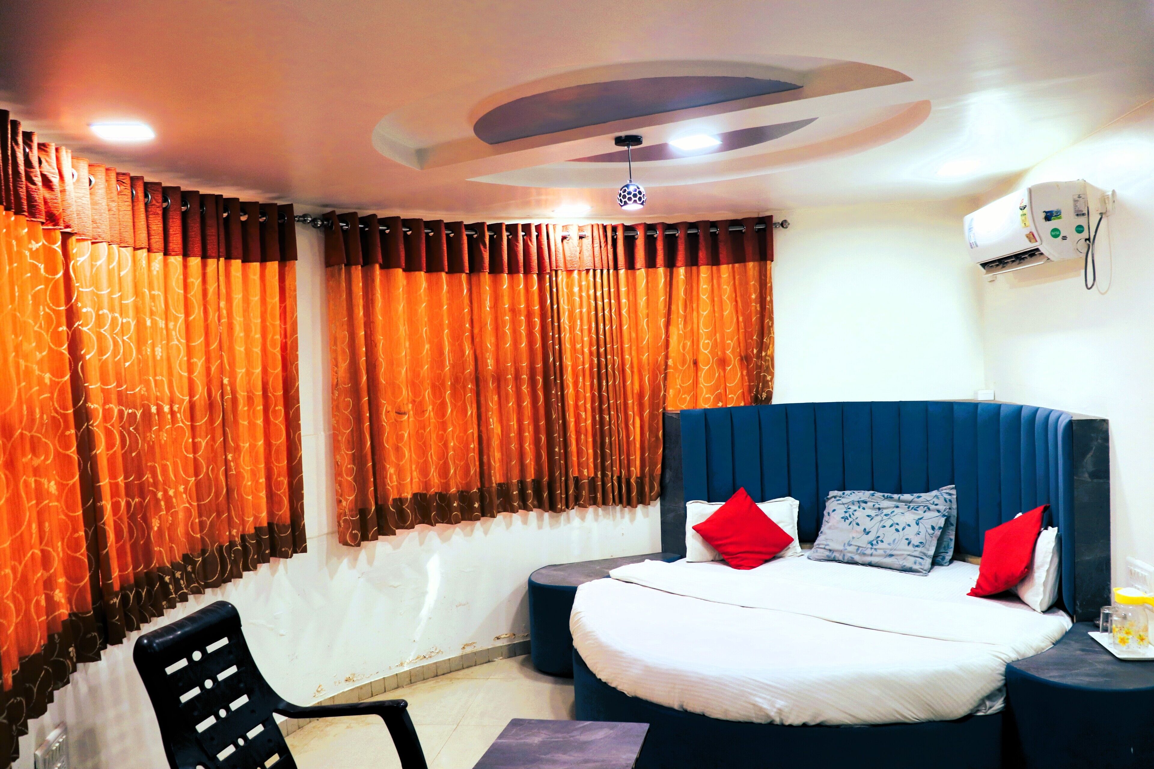 A bedroom with a bed, a chair, a nightstand, and an air conditioning unit.