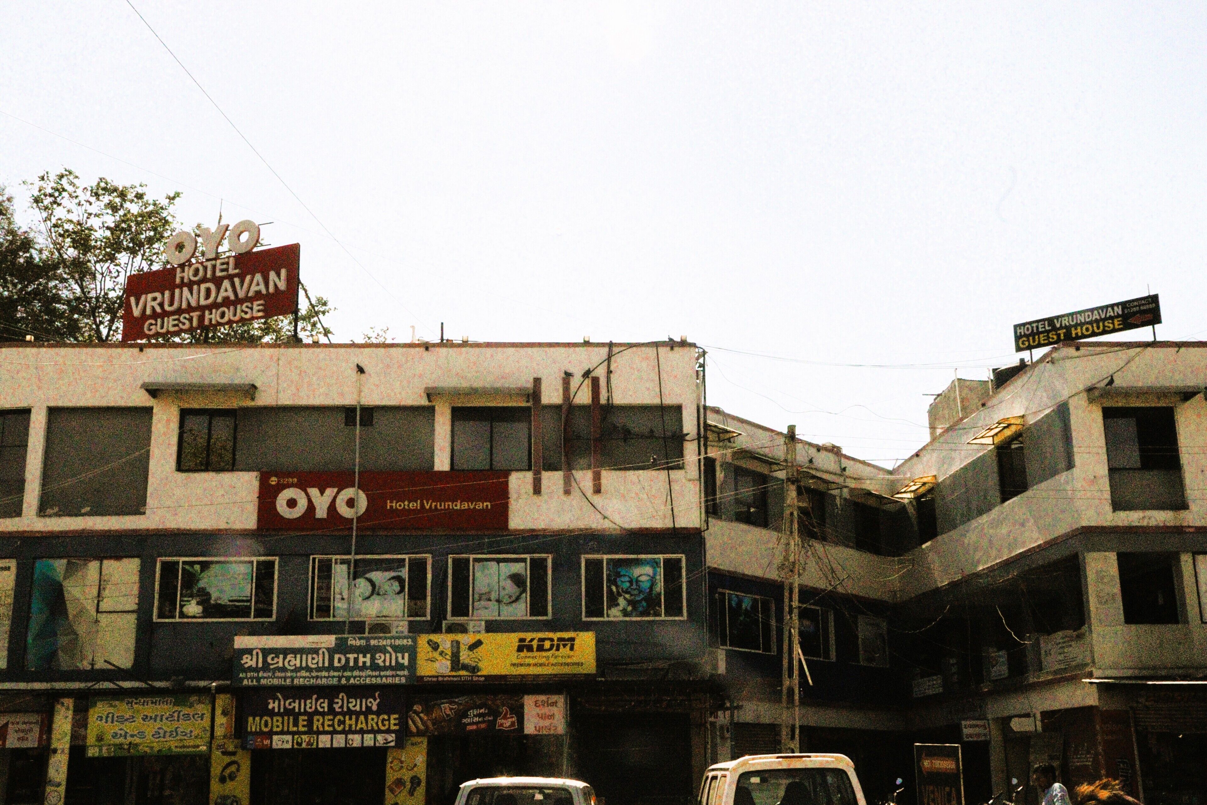 Un edificio con letreros que indican 'Oyo Hotel Vrundavan Guest House' y 'KDM Mobile Recharge'.