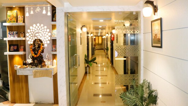 A hotel corridor with a reception area featuring a decorative shrine, a mirror, and a potted plant.