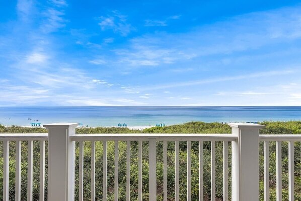 A view of a beach with a white fence in the foreground.