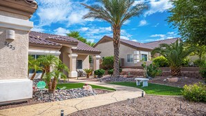 A residential area with houses, a pathway, and a well-maintained garden with palm trees and shrubs. - AMAZING Pool home with outdoor kitchen, firepit, and waterfall Close 2 Casinos!  (Bullhead City)