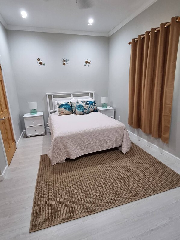 Une chambre à coucher avec un lit, des tables de chevet, un tapis et des rideaux.