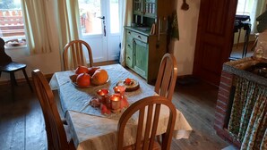 A dining area with a table set for four, a green cabinet, and a kitchen area visible through an open door. - In the middle of nature, an oasis of peace
 (Log Cezsoški)