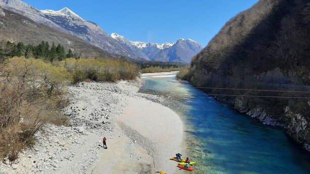 A river with kayaks, a rocky shore, and mountains in the background. - In the middle of nature, an oasis of peace
 (Log Cezsoški)