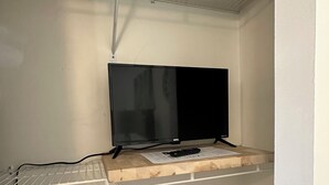 Een kamer met een witte muur, een plank met een flatscreen-televisie en een stopcontact.