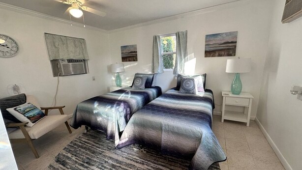Een slaapkamer met twee bedden, een plafondventilator, een klok en kunstwerken aan de muur.