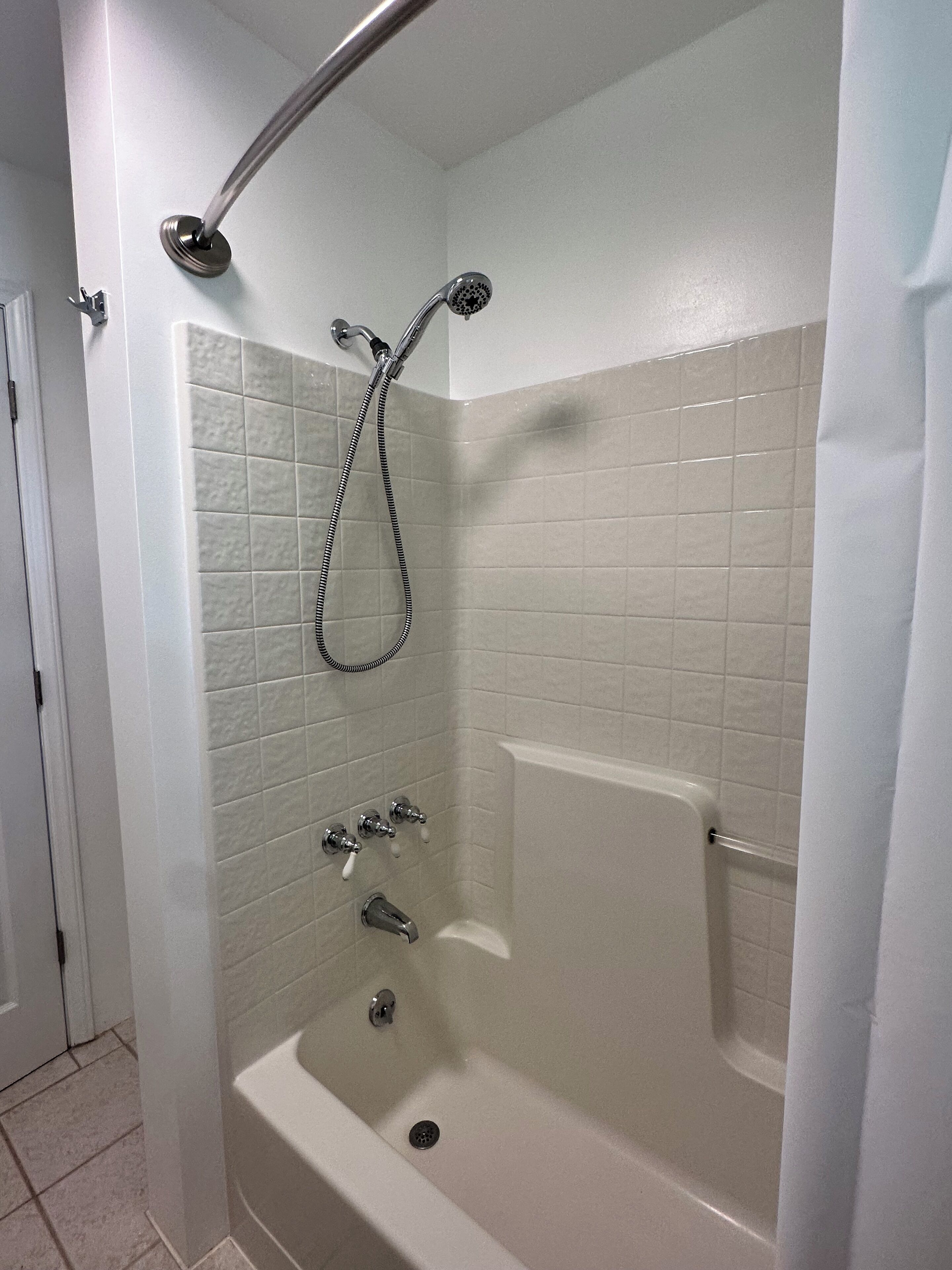 Een douche met lage drempel, een handdouche, een inloopbad en een muur-geplaatste kraan.