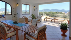 A spacious patio with a dining area, seating, and a view of the mountains. - Casa Amor by Wonderful Italy (Olbia)