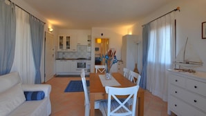 A compact living space with a dining area, kitchenette, and a small sailboat model on a dresser. - Casa Amor by Wonderful Italy (Olbia)