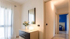 Une chambre à coucher moderne avec une commode, un miroir et une table de chevet agrémentée de fleurs.