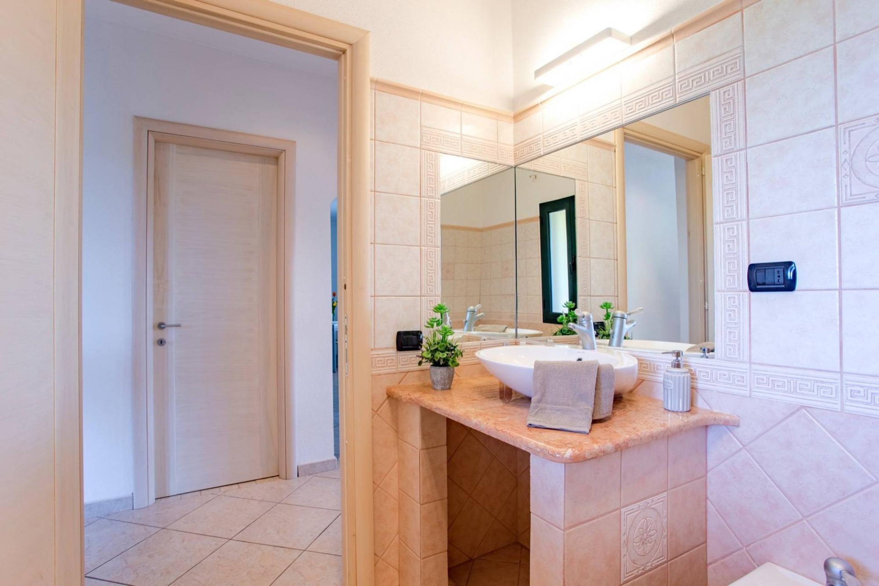 A modern bathroom with a large sink, mirror, and decorative tiles.